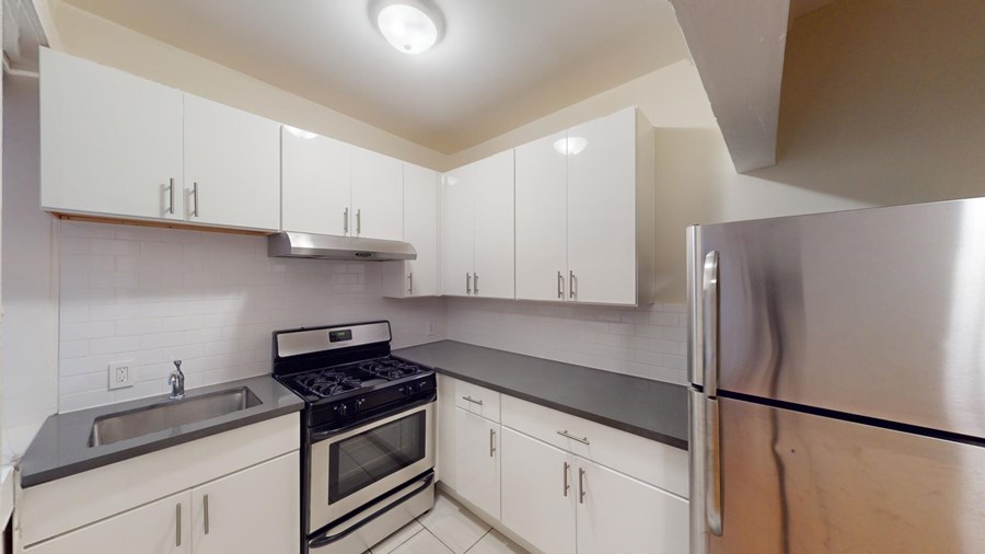 A kitchen with white cabinets and a stainless steel refrigerator.