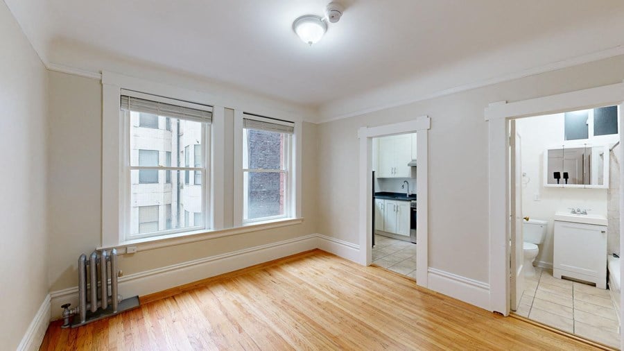 an empty living room with three windows and a wood floor