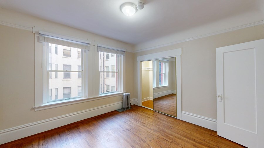 A room with a wooden floor and a large mirror on the wall.