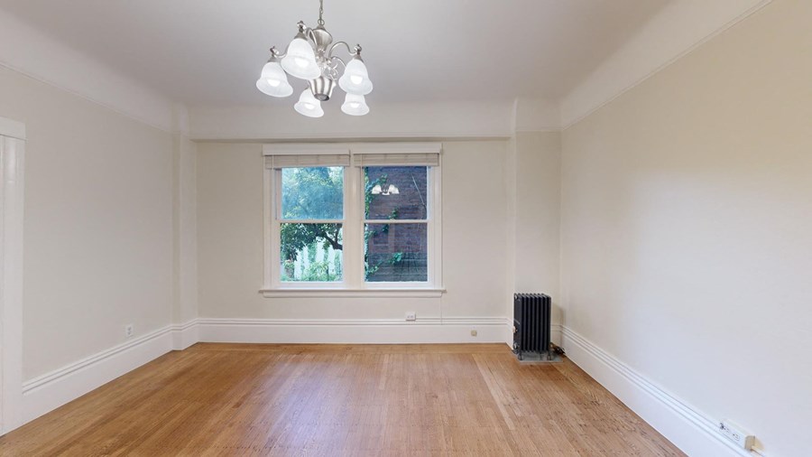 an empty living room with a window and a radiator