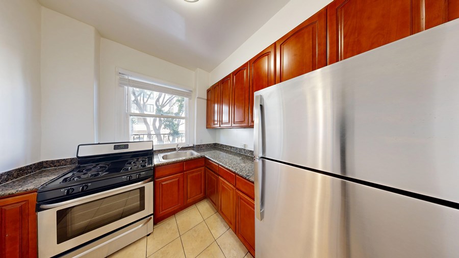 A kitchen with a stove, refrigerator, and cabinets.