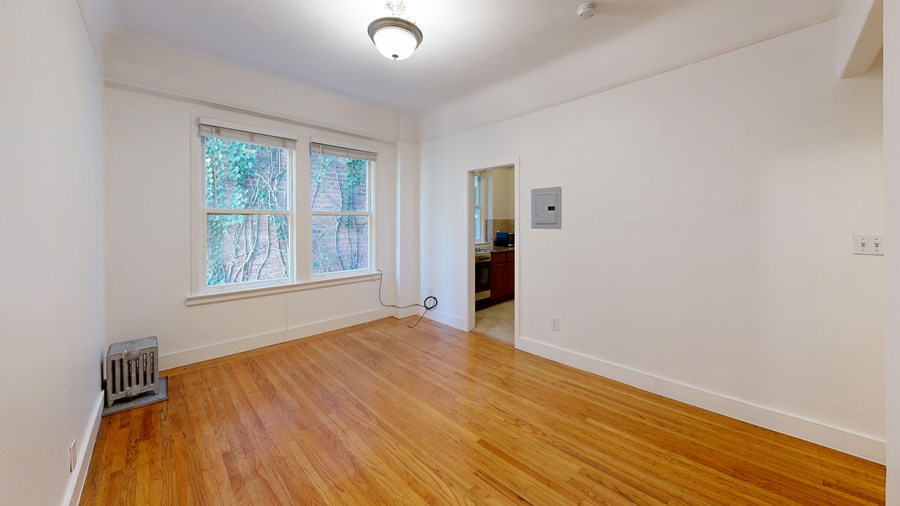 A room with wooden floors and a window with a view of trees outside.