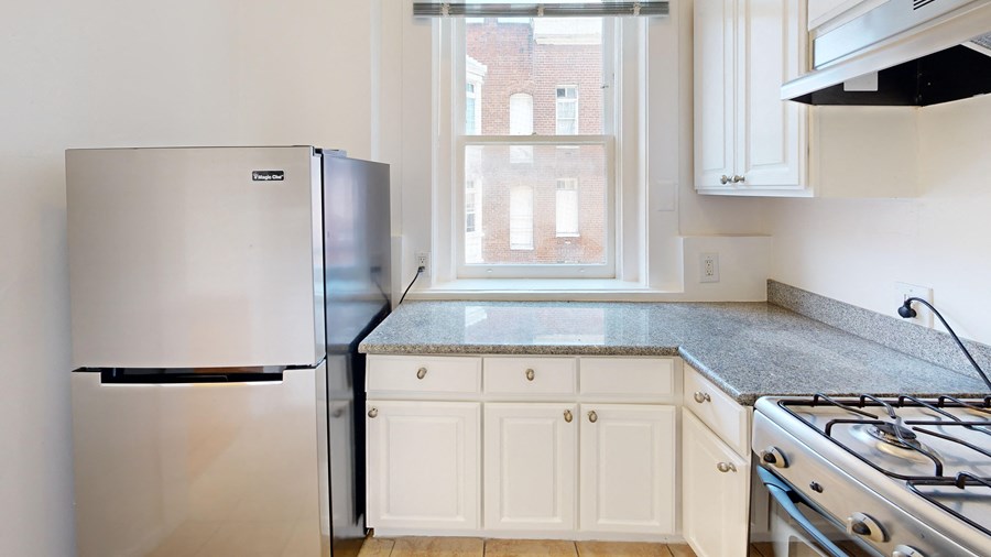 a kitchen with white cabinets and stainless steel appliances and a window