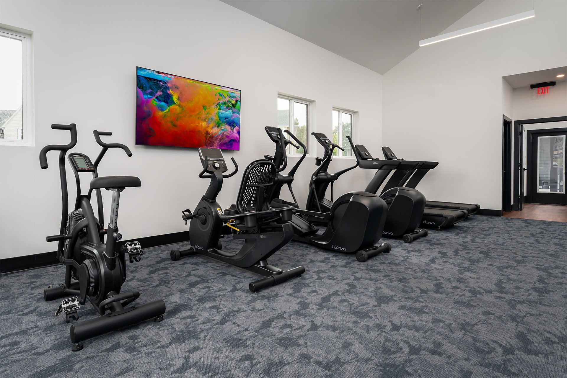 A gym with a row of stationary bikes and a colorful painting on the wall.