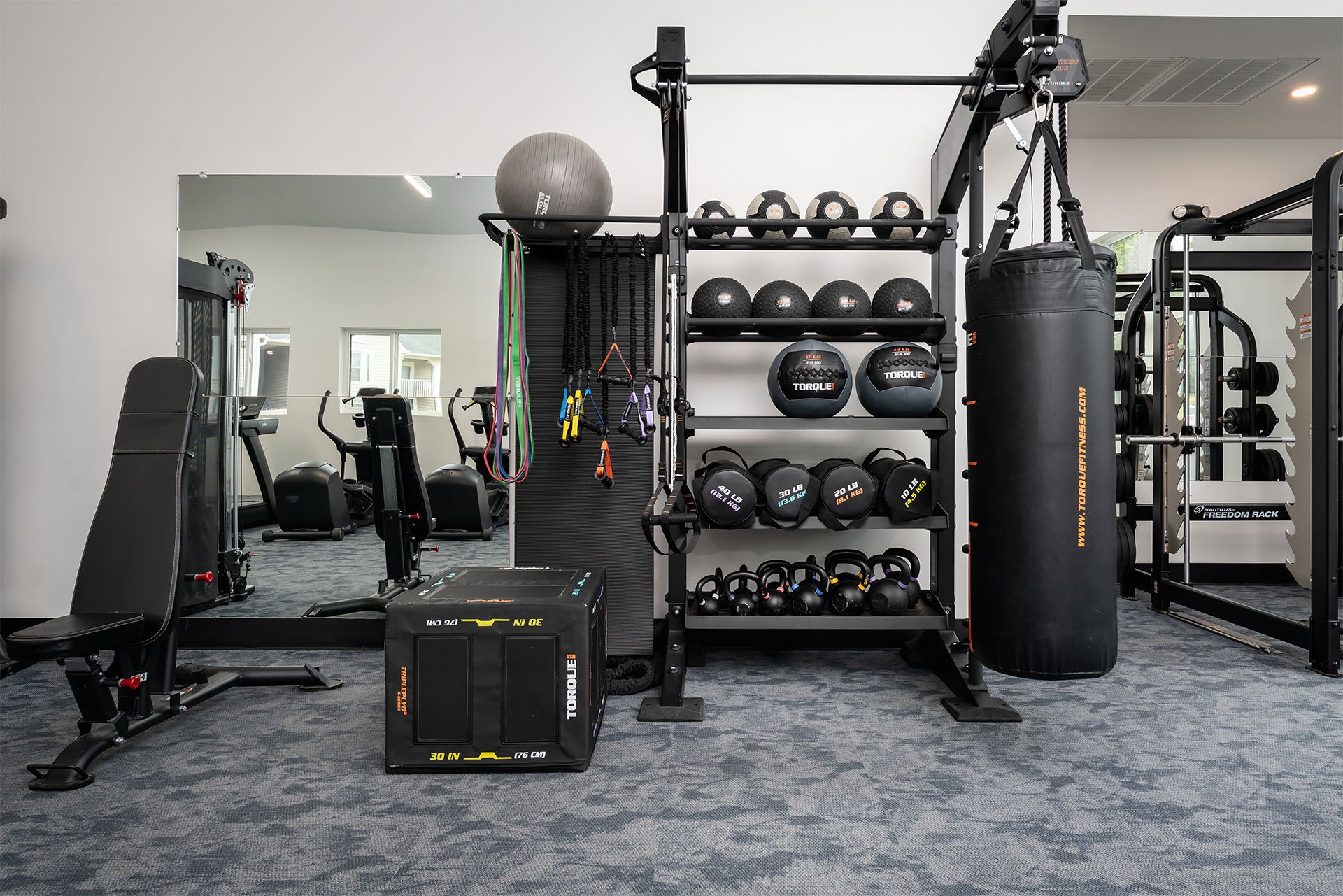 A gym with a variety of equipment including weights and a punching bag.
