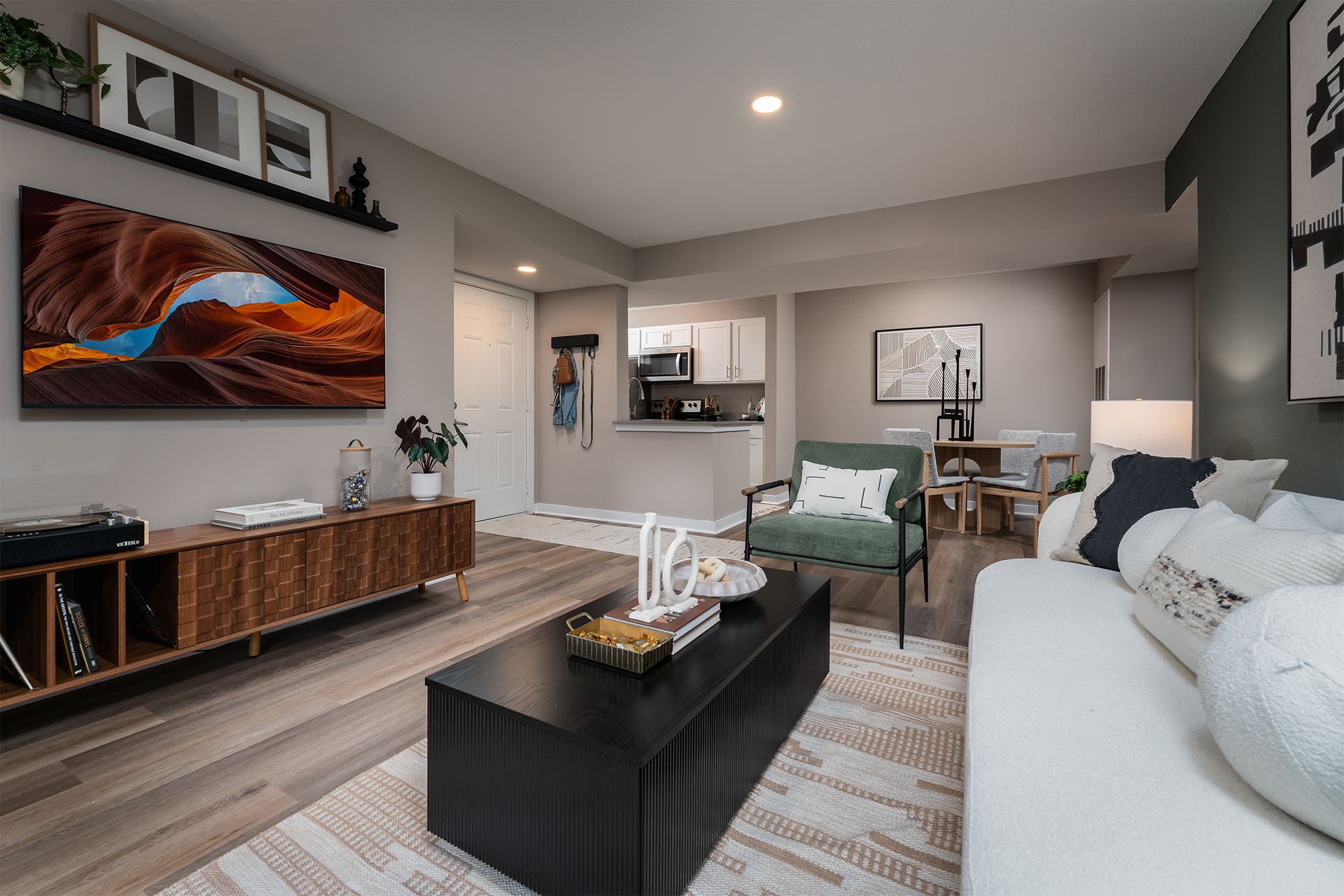 A modern living room with a black coffee table and a large abstract painting on the wall.