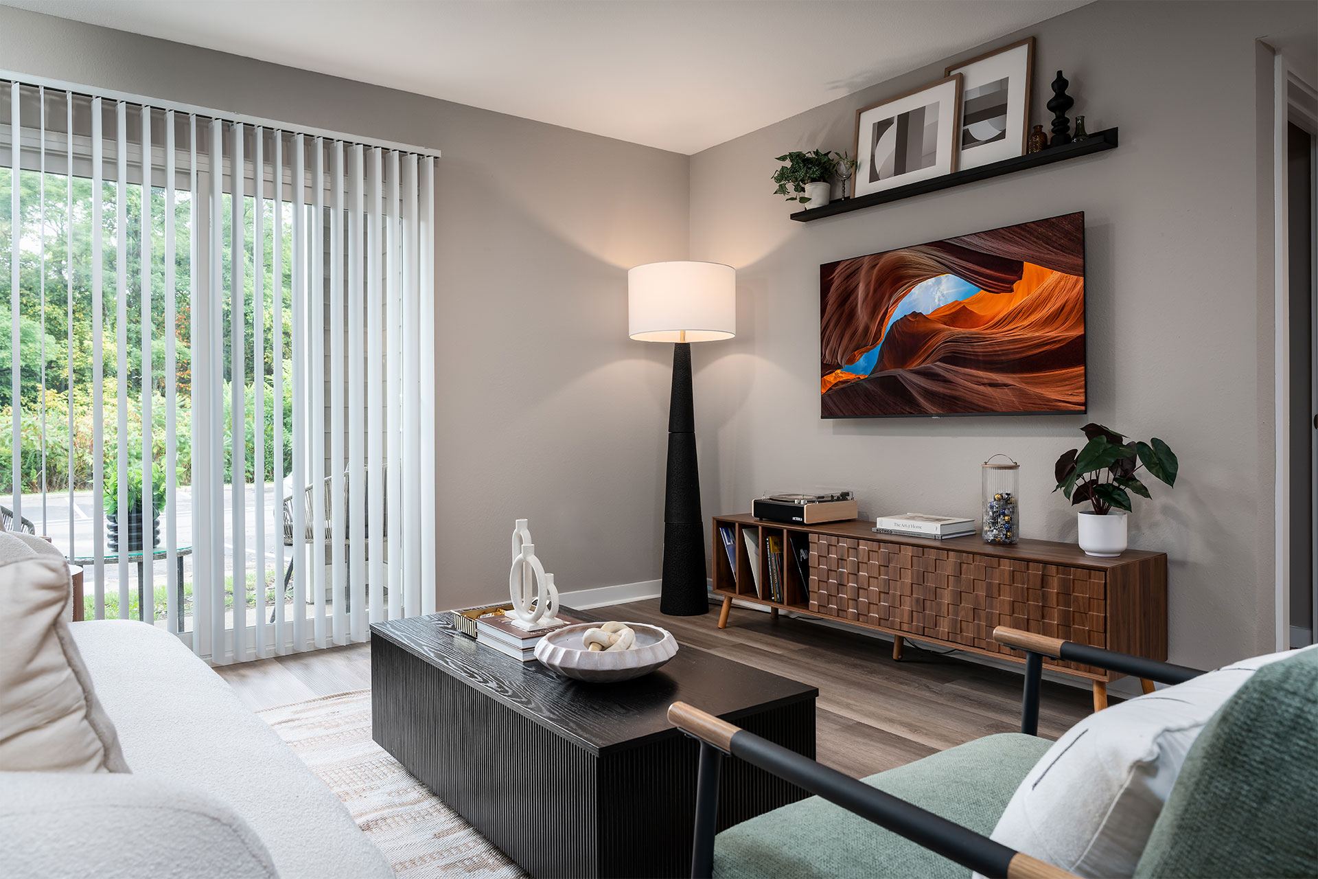 A modern bedroom with a large bed, a nightstand, a lamp, and a painting on the wall.