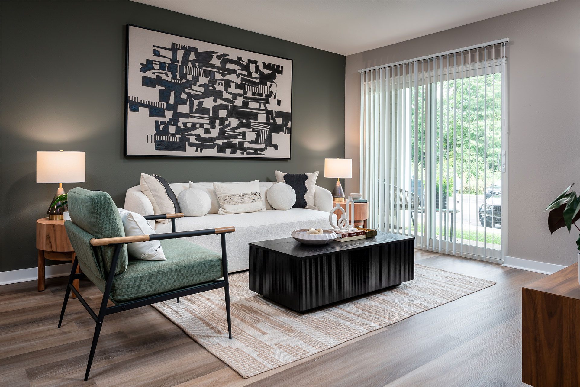 A living room with a green chair and a black and white abstract painting on the wall.