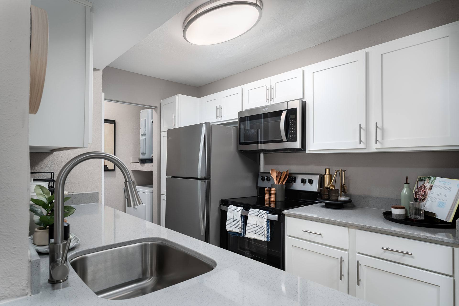 A modern kitchen with a stainless steel sink and white cabinets.