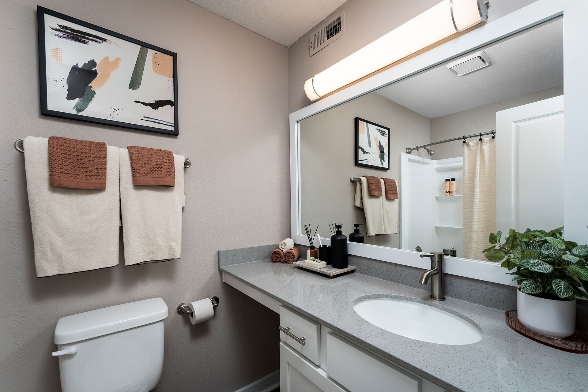 A bathroom with a toilet, sink, and mirror.