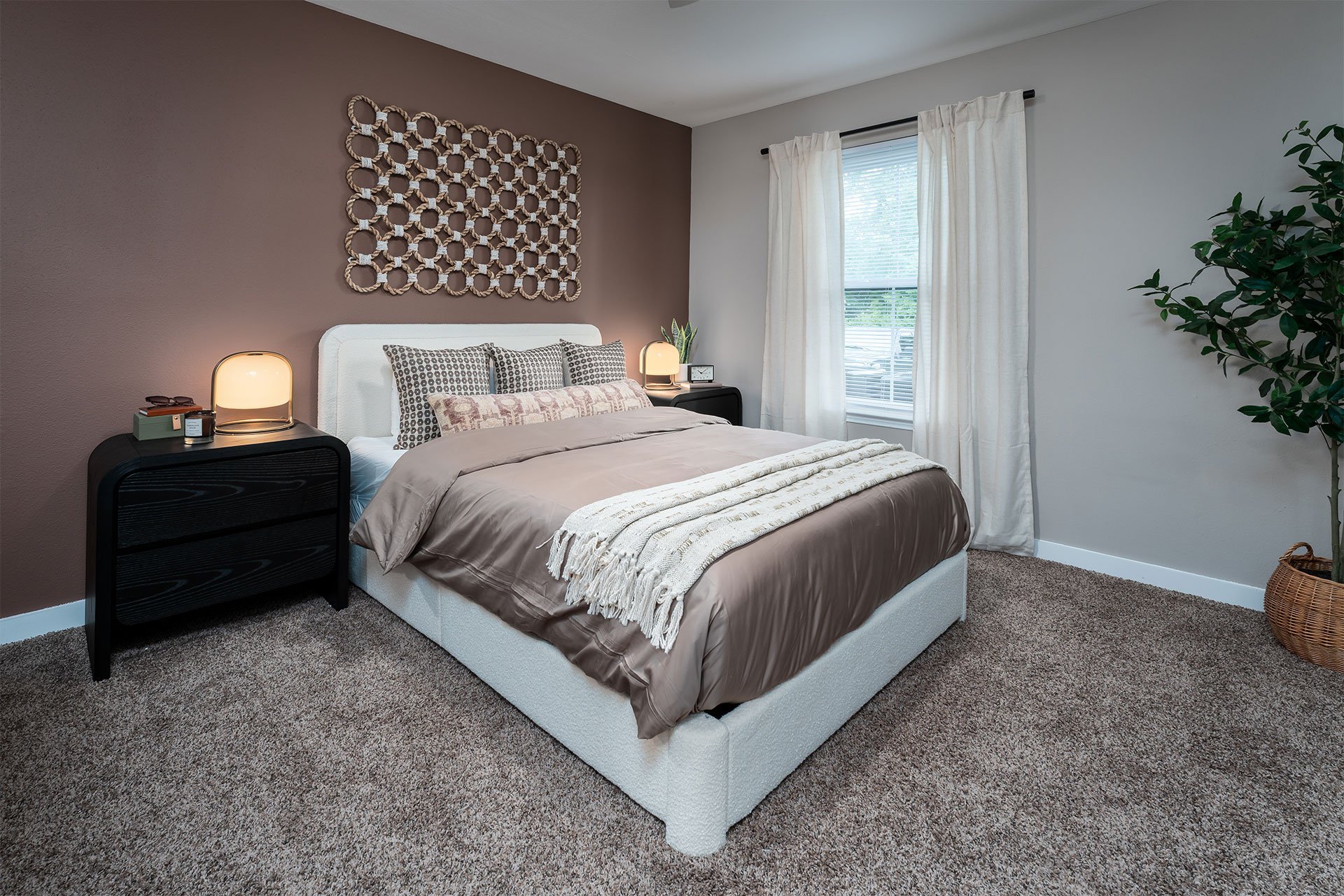 A bedroom with a large bed and a window with curtains.