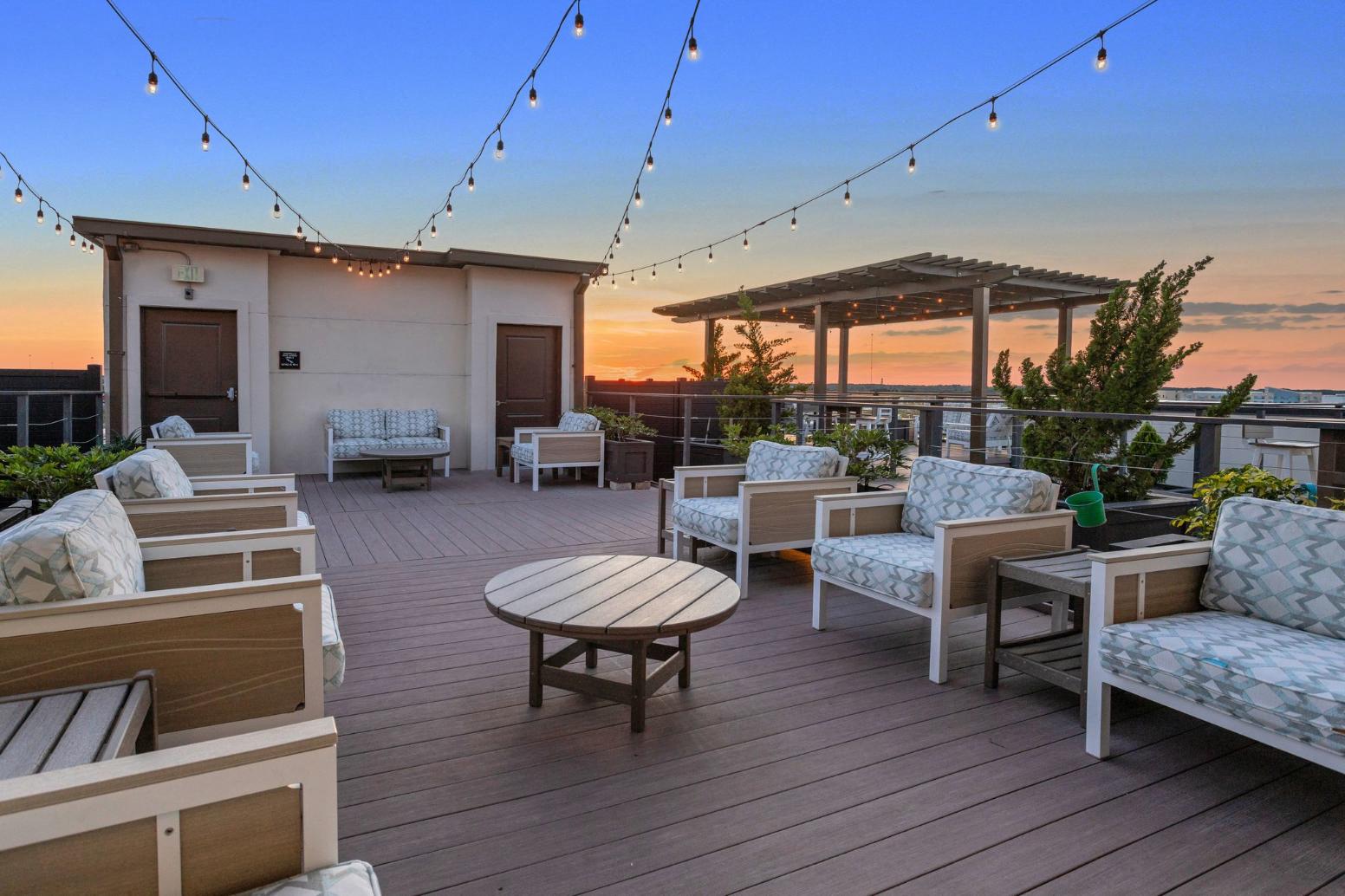 a roof deck with a table and chairs and a sunset