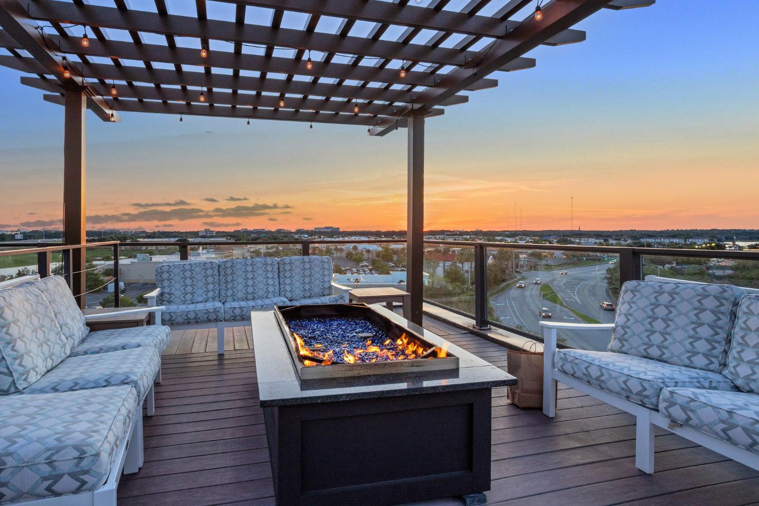 a rooftop deck with a fire pit and couches and a view of the city