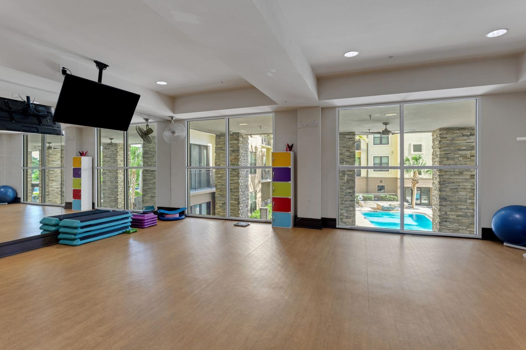 a workout room with a tv and a pool in the distance