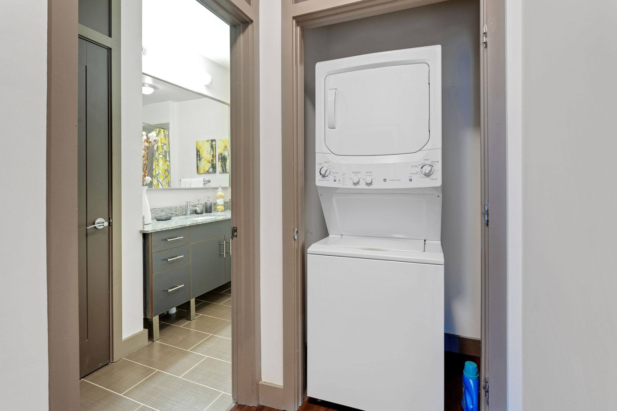 a white washer and dryer in a closet in a bathroom