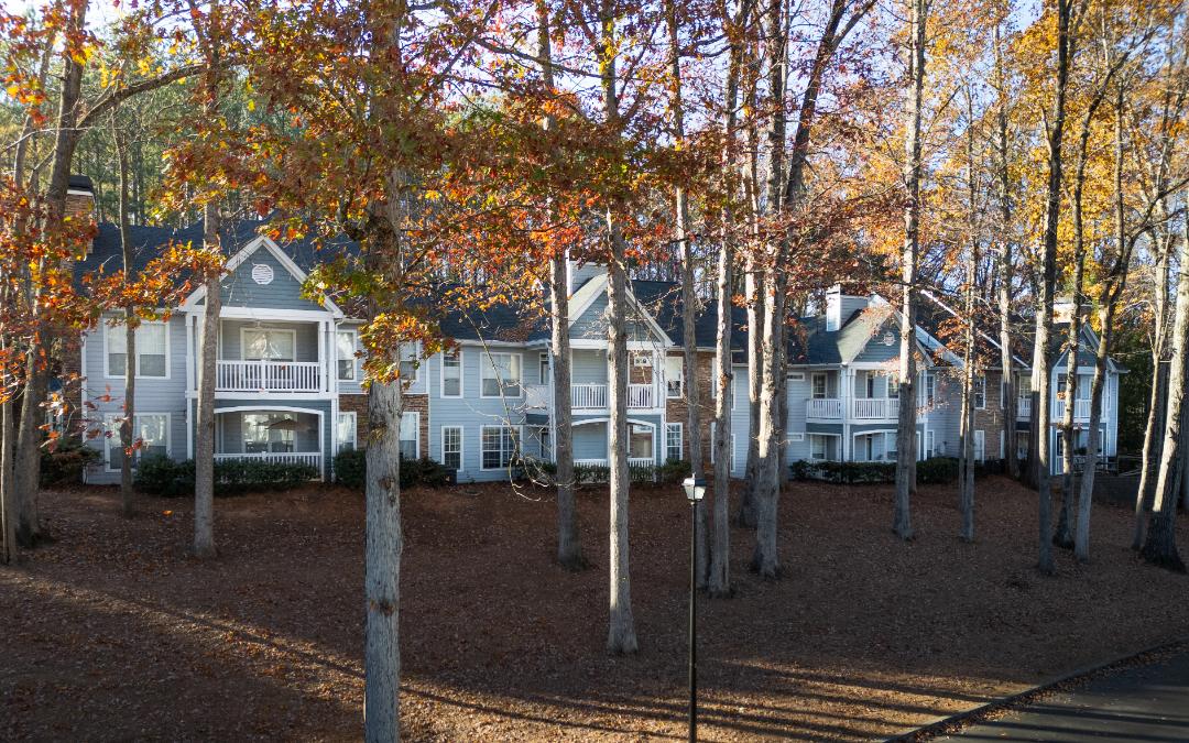 A row of houses with trees in front.