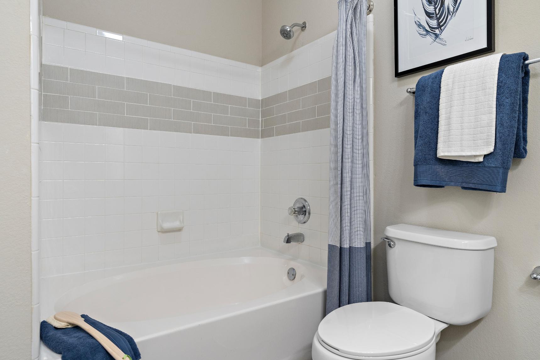 A white toilet sits next to a white bathtub in a bathroom.