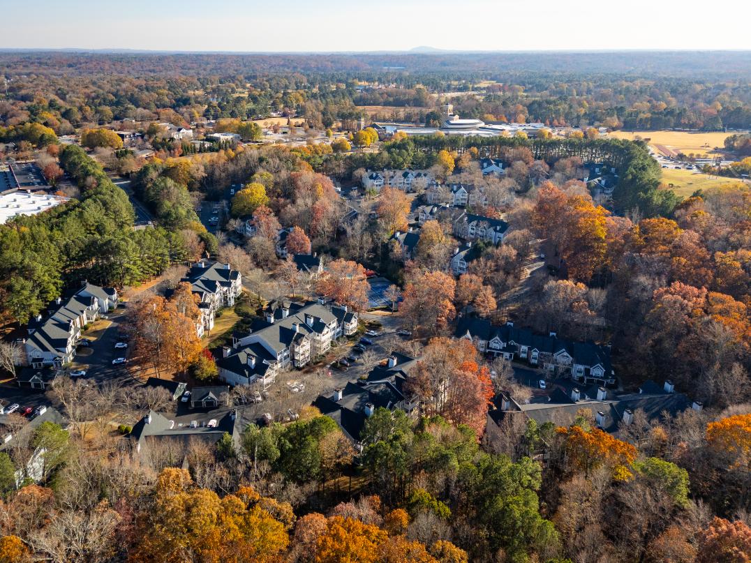 A bird's eye view of a residential area surrounded by trees in autumn.