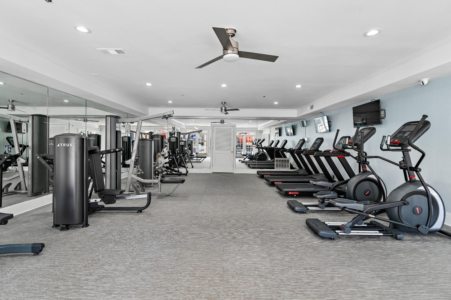 A gym with treadmills, elliptical machines, and other exercise equipment.