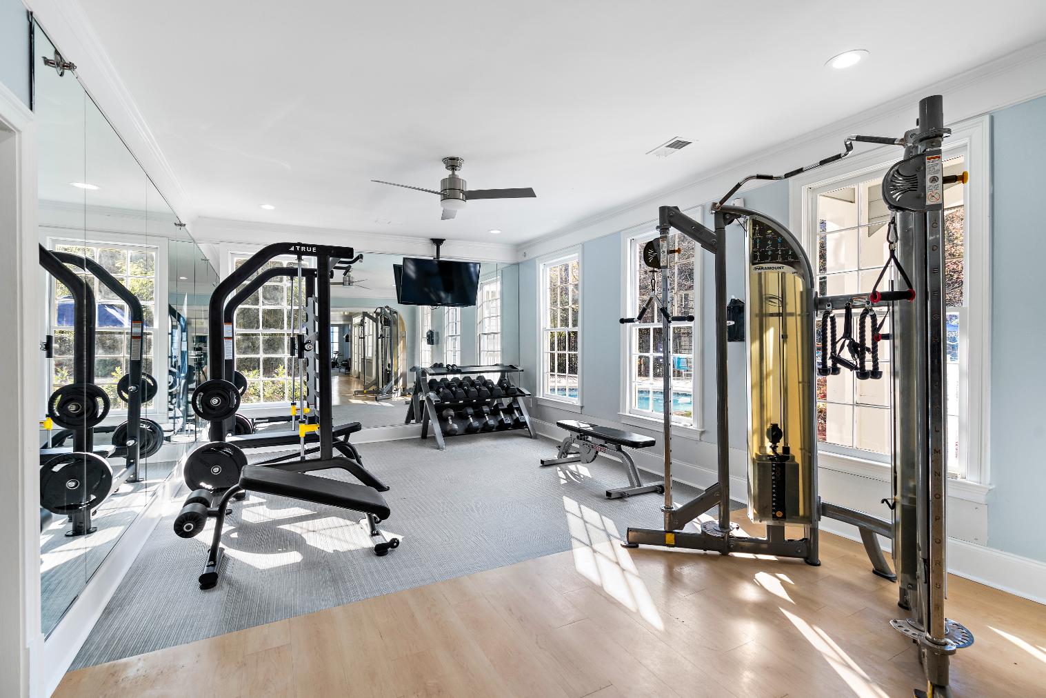 A spacious gym with a variety of equipment including a squat rack, bench, and weights.