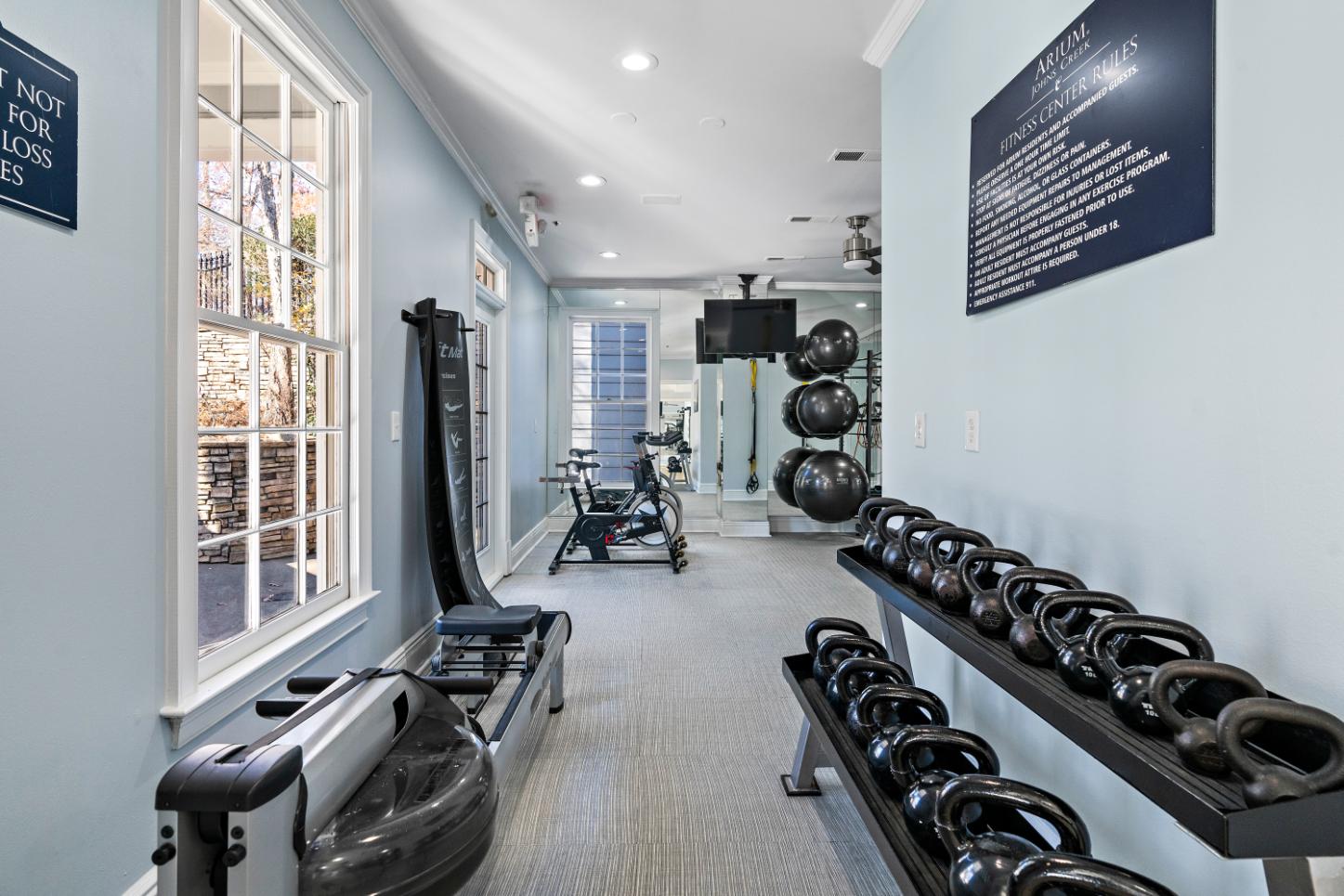 A gym with a row of kettlebells on the wall.