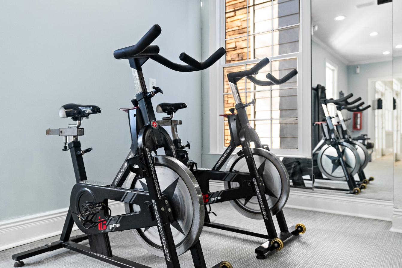 A row of stationary bikes are lined up in a gym.