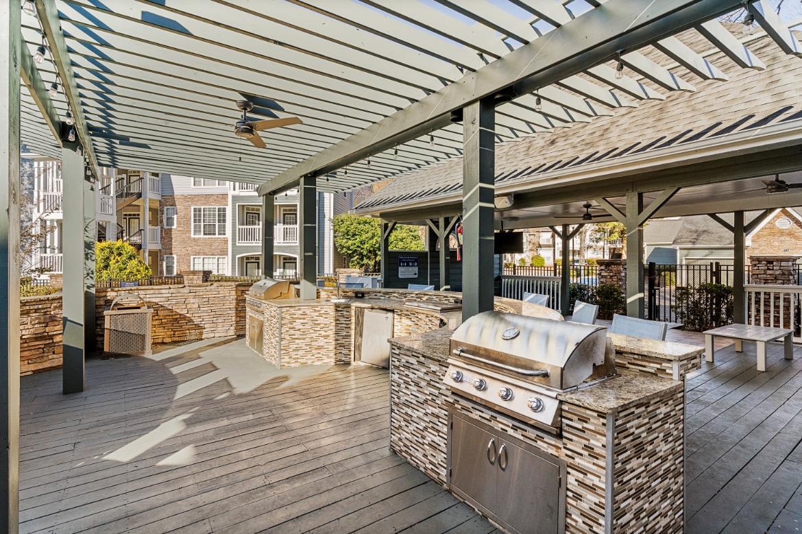 A barbecue grill is on a wooden deck.