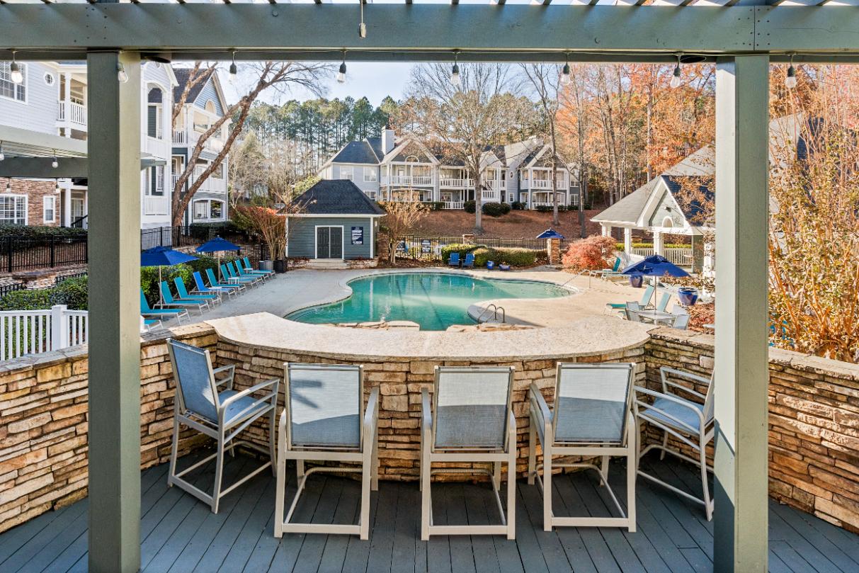 A pool surrounded by chairs and a wooden deck.