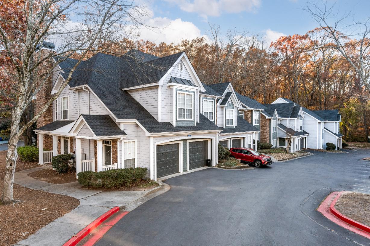 A row of houses with a red car parked in the driveway.