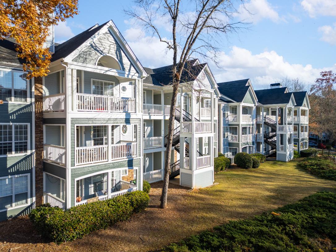 A row of white houses with balconies and a tree with yellow leaves.