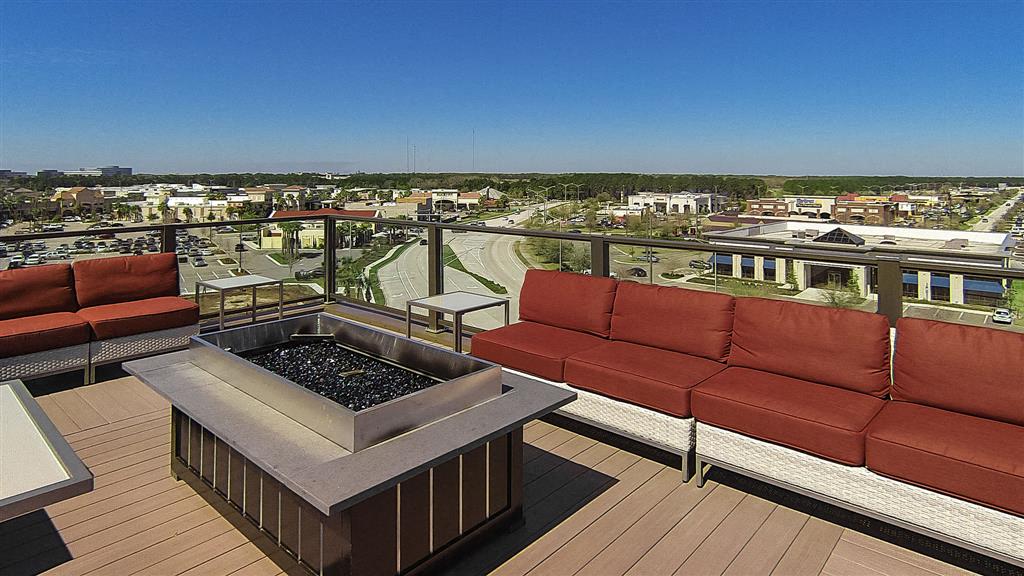 a view of a city from a balcony with red couches and a fire pit