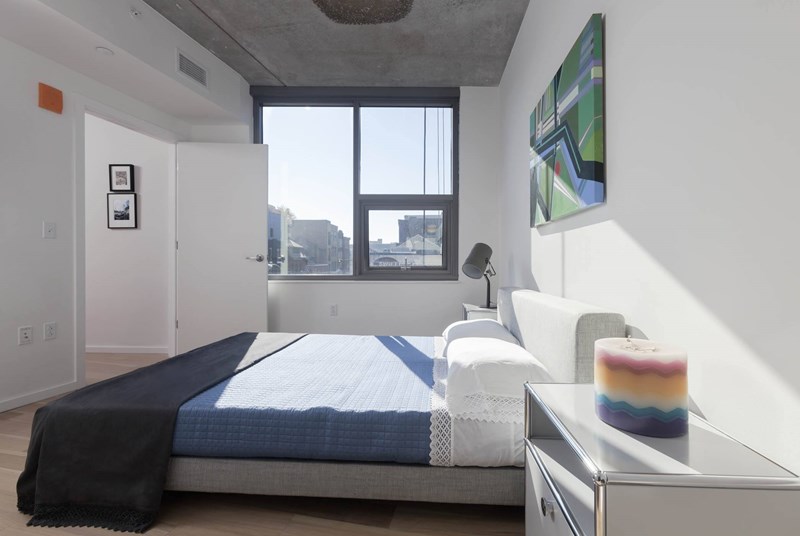 A bedroom with a bed, a nightstand, and a window.