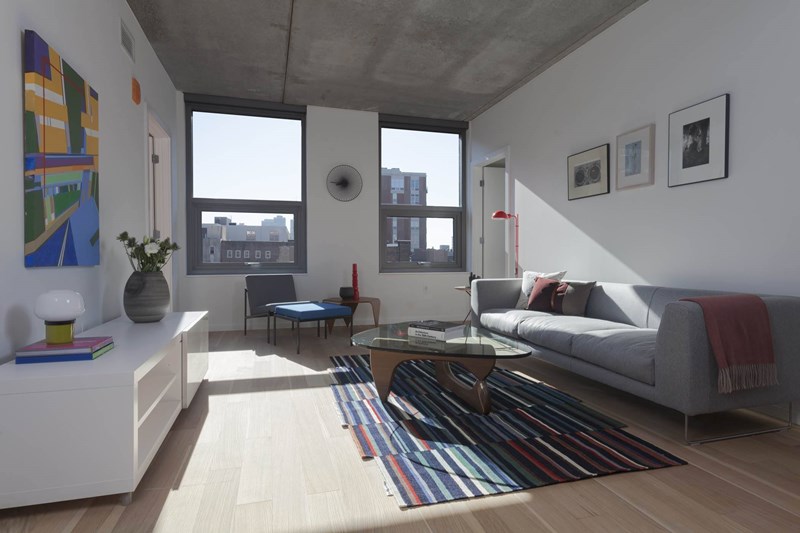 A living room with a grey couch, a coffee table, and a large window.