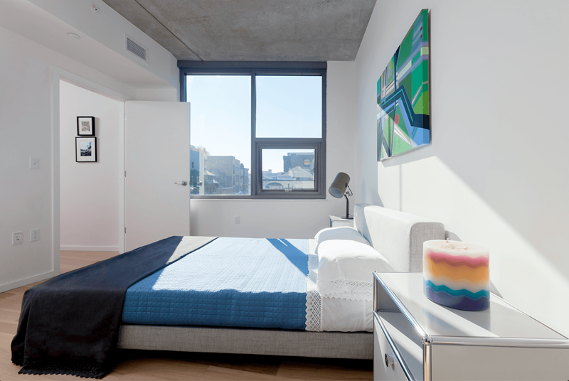 A bedroom with a bed, a nightstand, and a window.