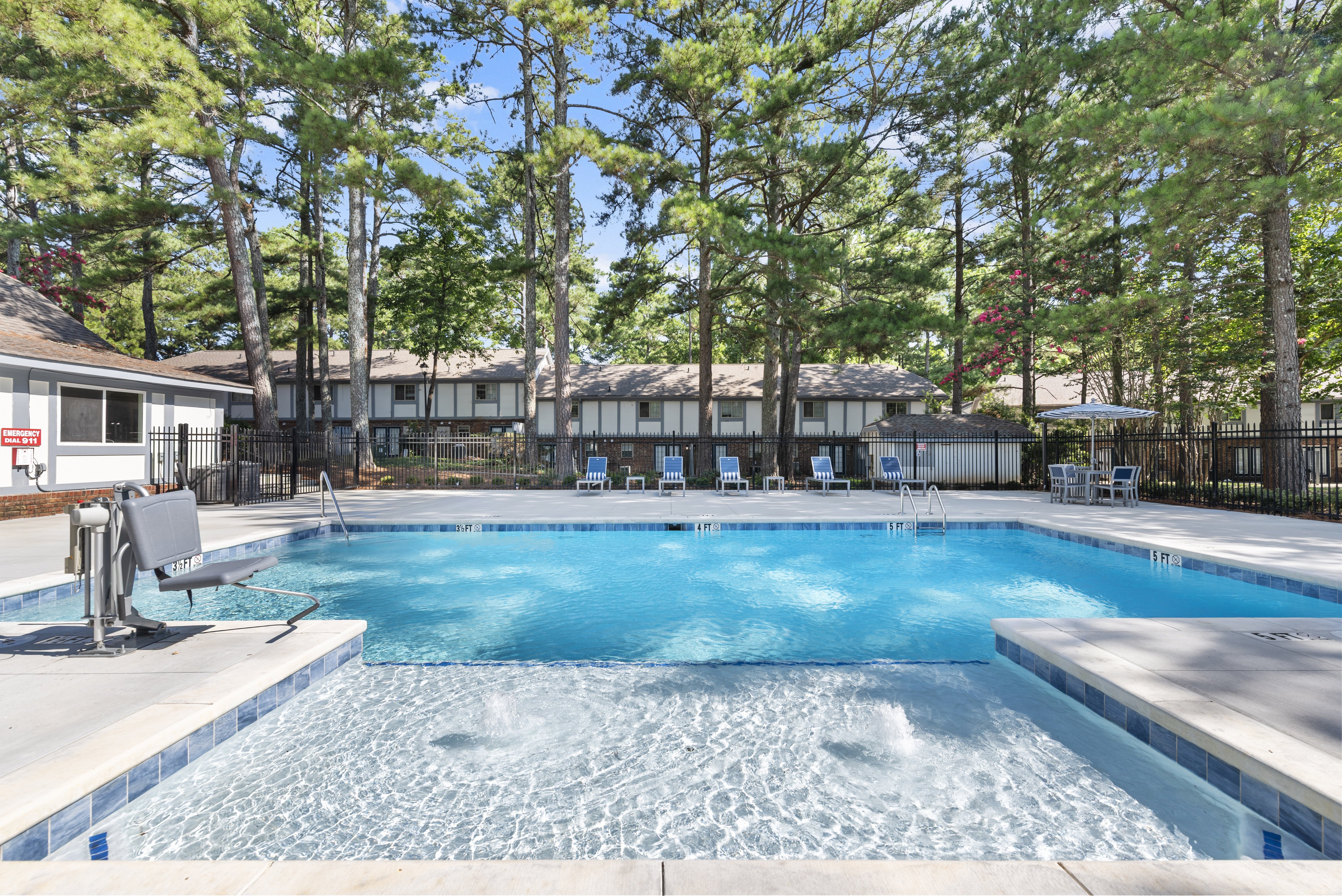 A large swimming pool surrounded by trees and chairs.