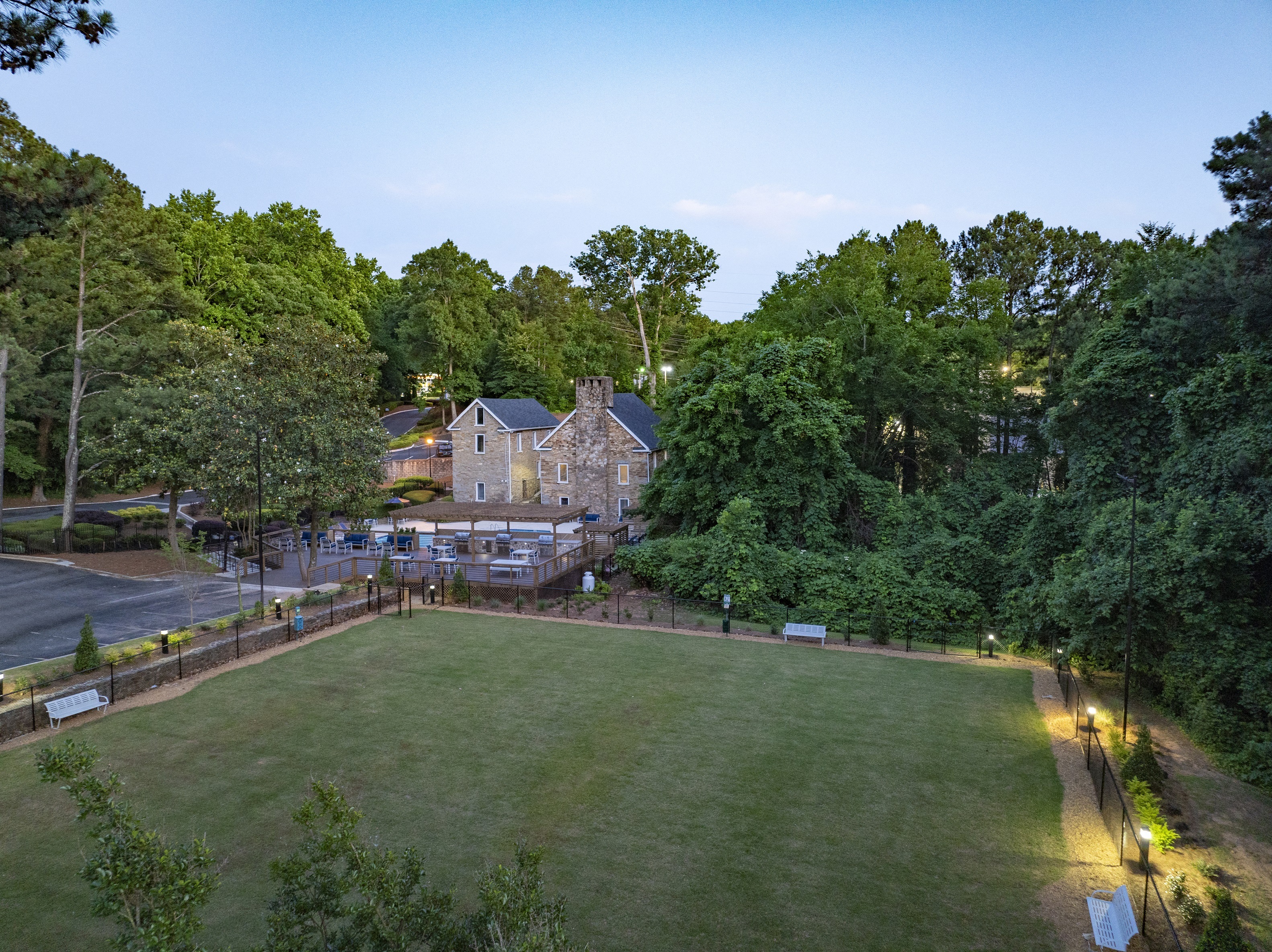 Stone building nestled among trees, with a grassy lawn in the foreground at Mill House at East Cobb offers townhomes near Kennestone Hospital in Marietta, GA.