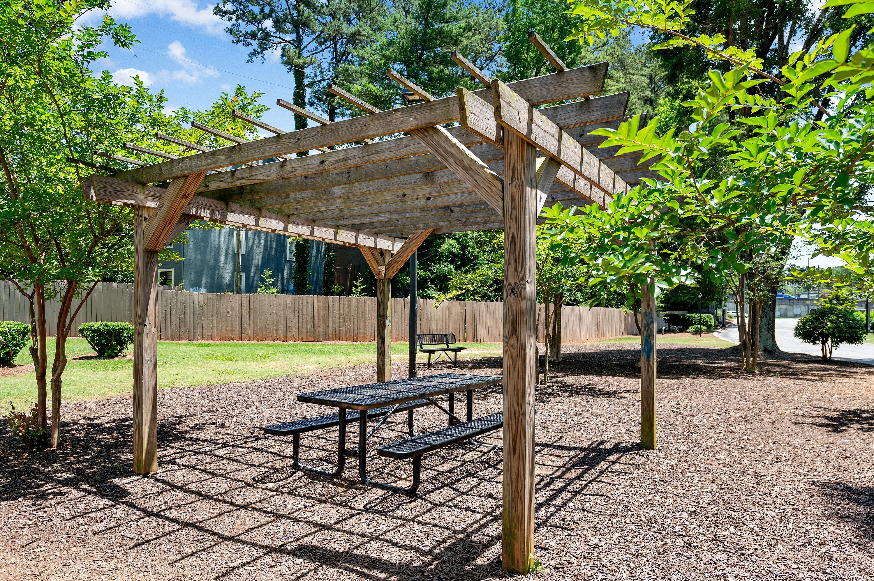 a picnic area with a bench and a pergola at Dunwoody Glen in Atlanta, GA.