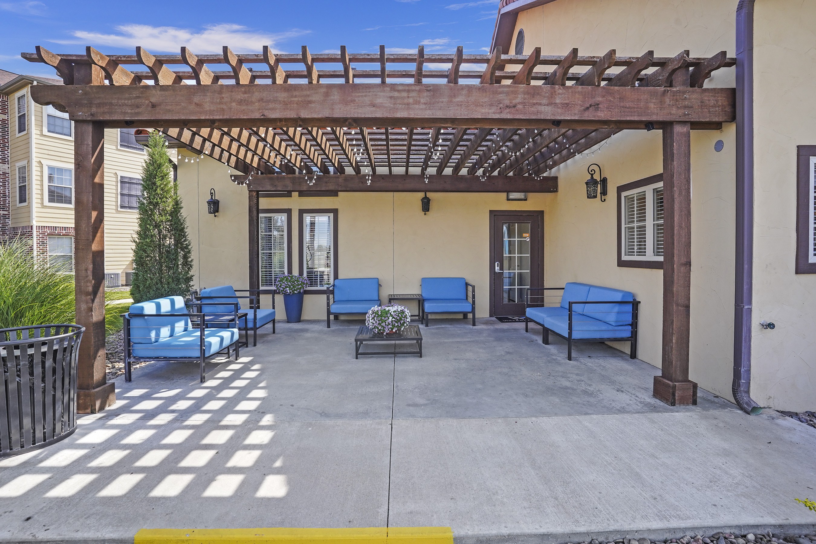 A patio with a pergola and blue cushioned seating.