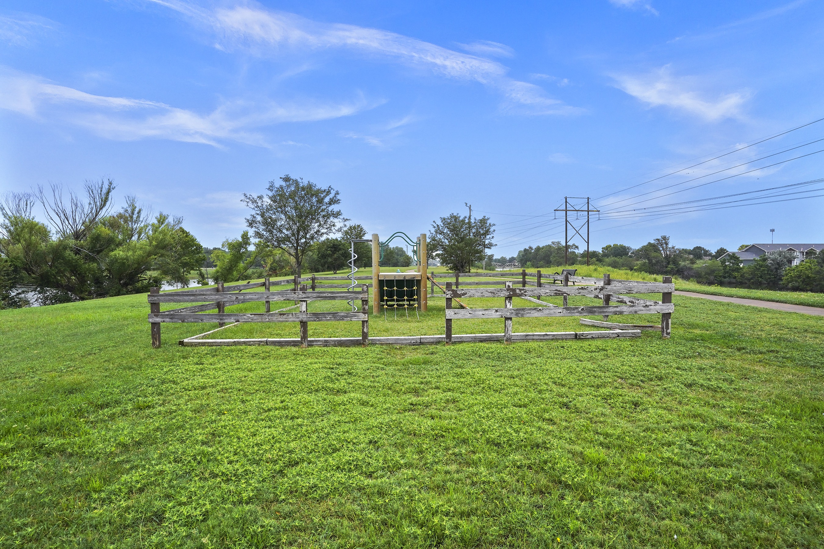 A wooden fence in a grassy field under a blue sky.