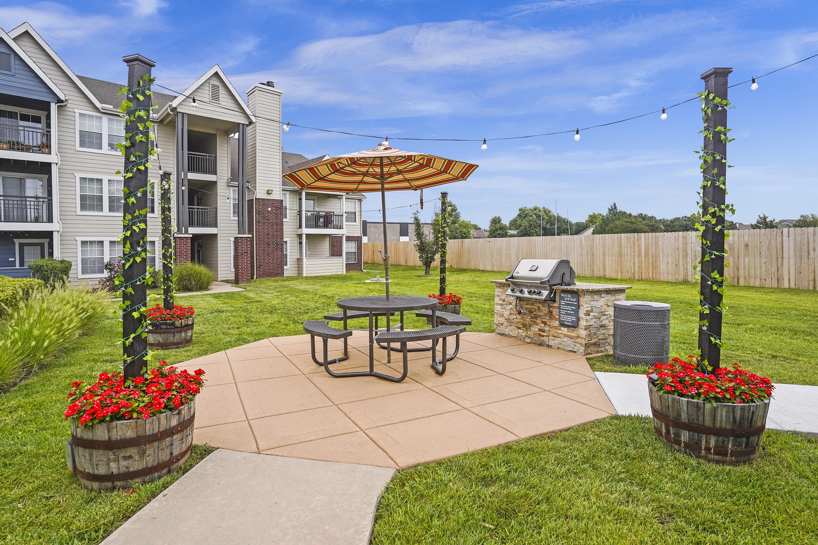 A patio with a table and chairs and a bench with flower pots on it.