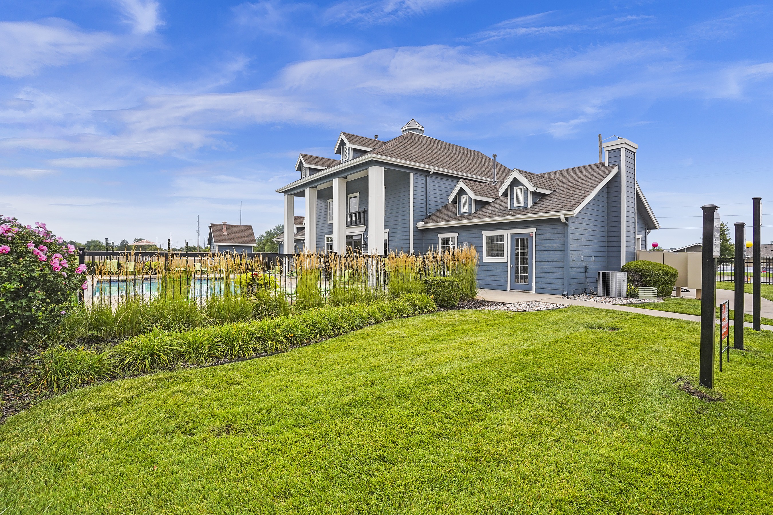 A house with a well-maintained lawn and a pool in the background.