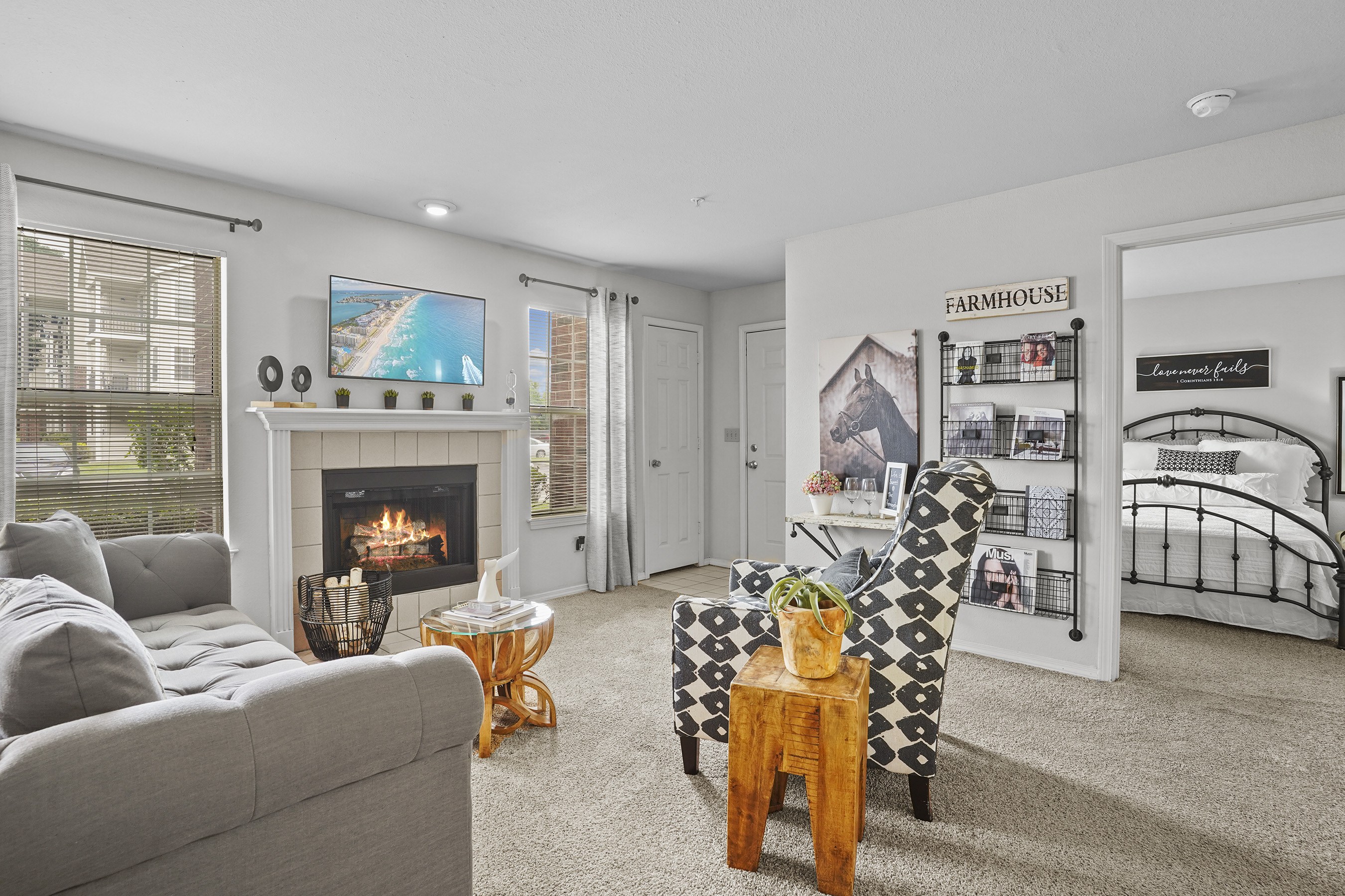 A living room with a grey couch, a fireplace, and a TV on the wall.
