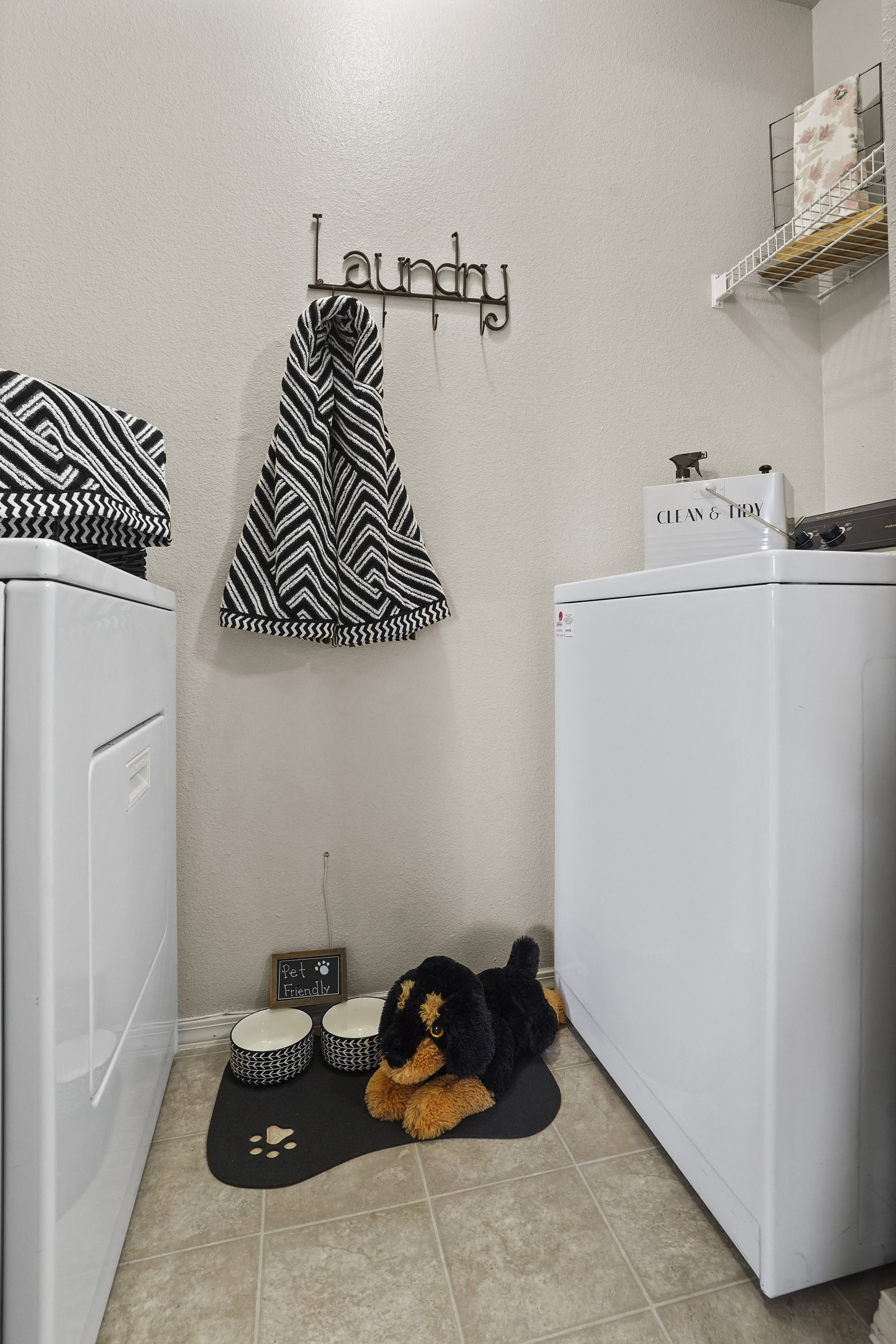 Laundry room with a washer and dryer, a towel, and a dog.