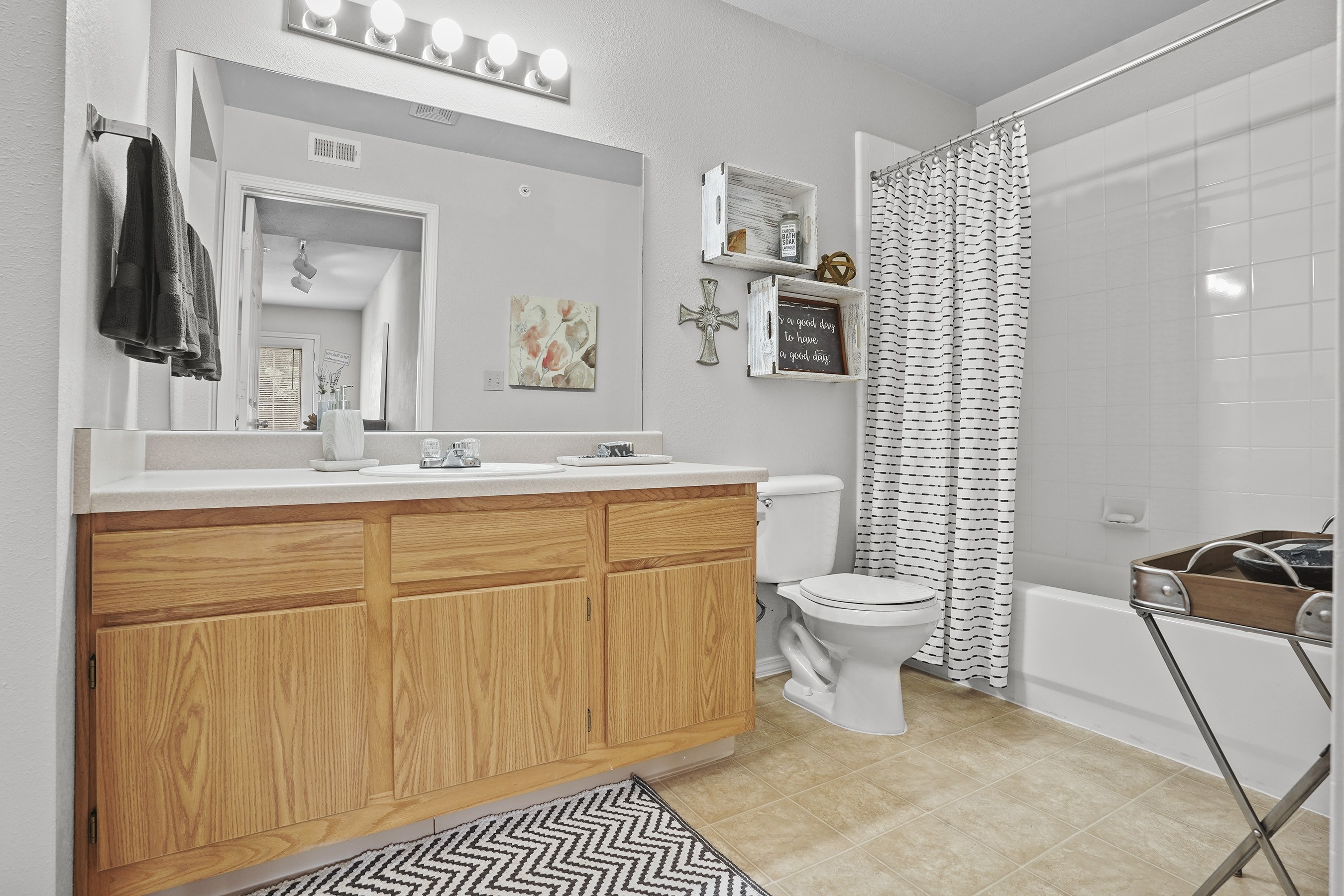 A bathroom with a wooden vanity and a mirror above it.