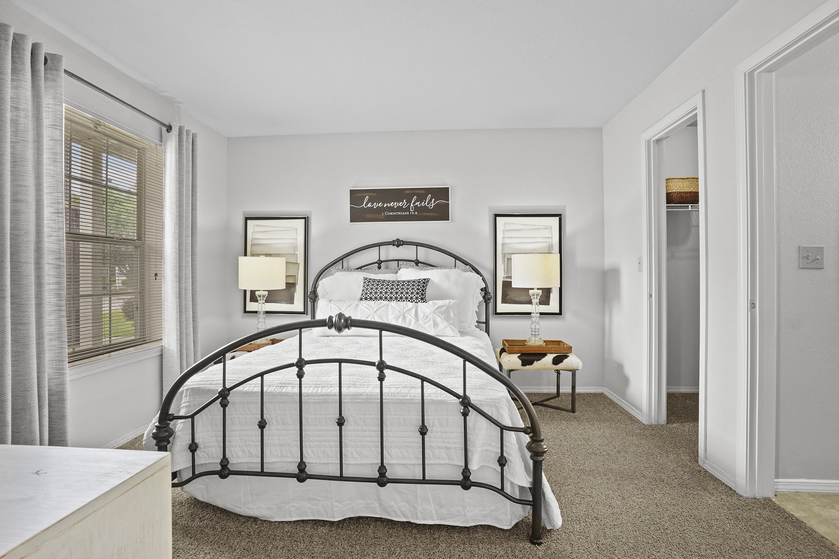 A bedroom with a large bed and a window with curtains.