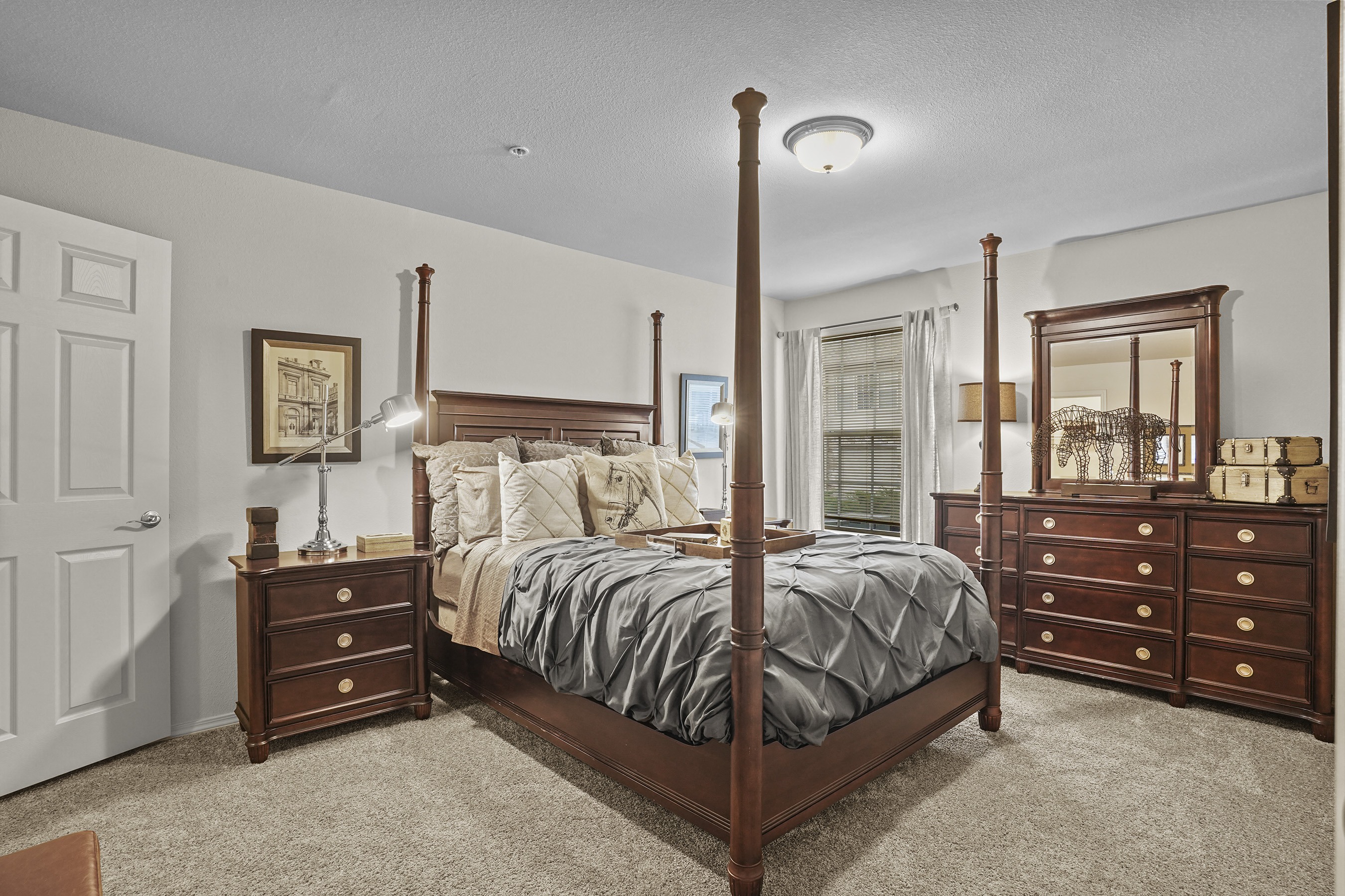 A bedroom with a large bed, a dresser, and a mirror.