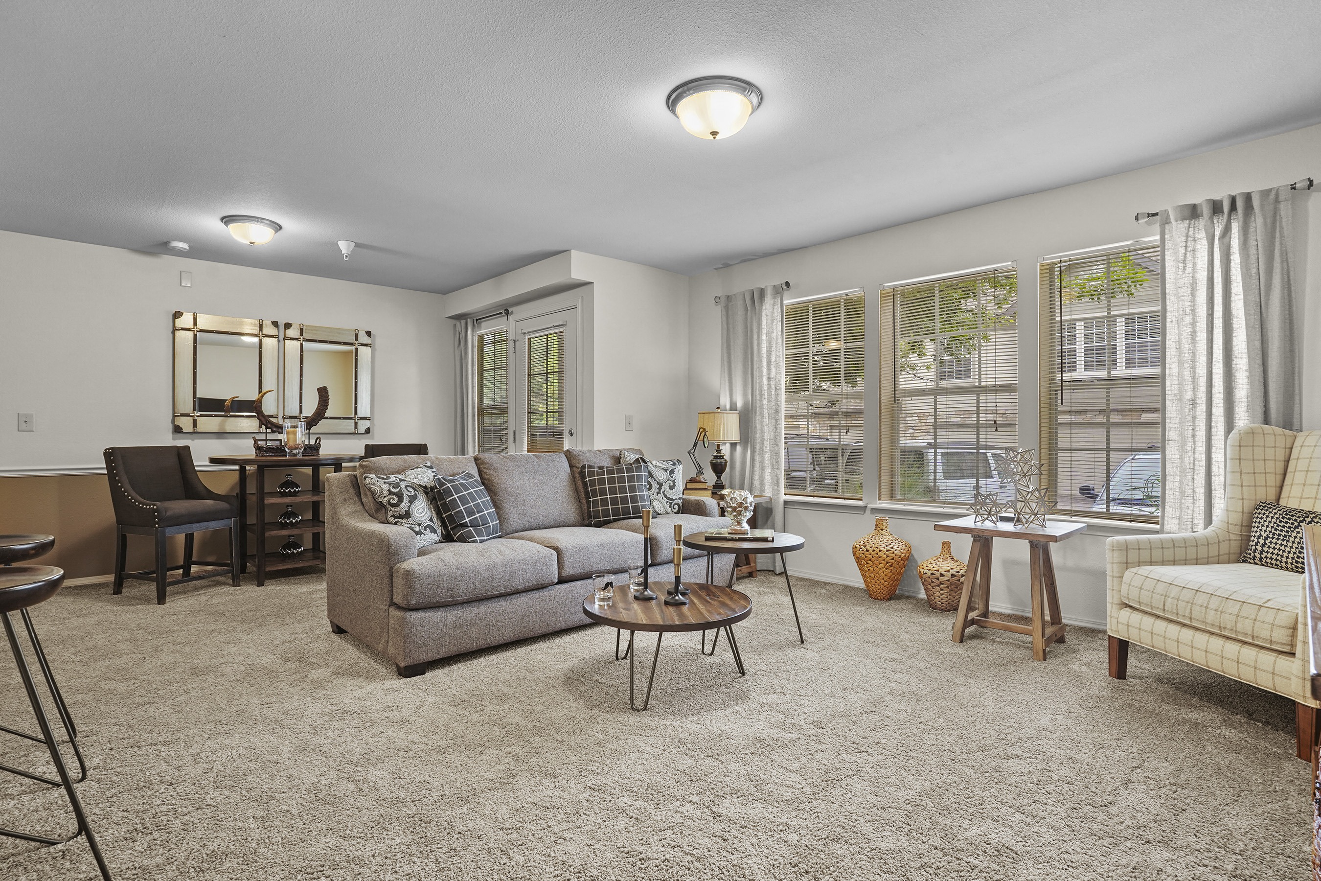 A living room with a grey couch, a chair, a table, and a mirror.