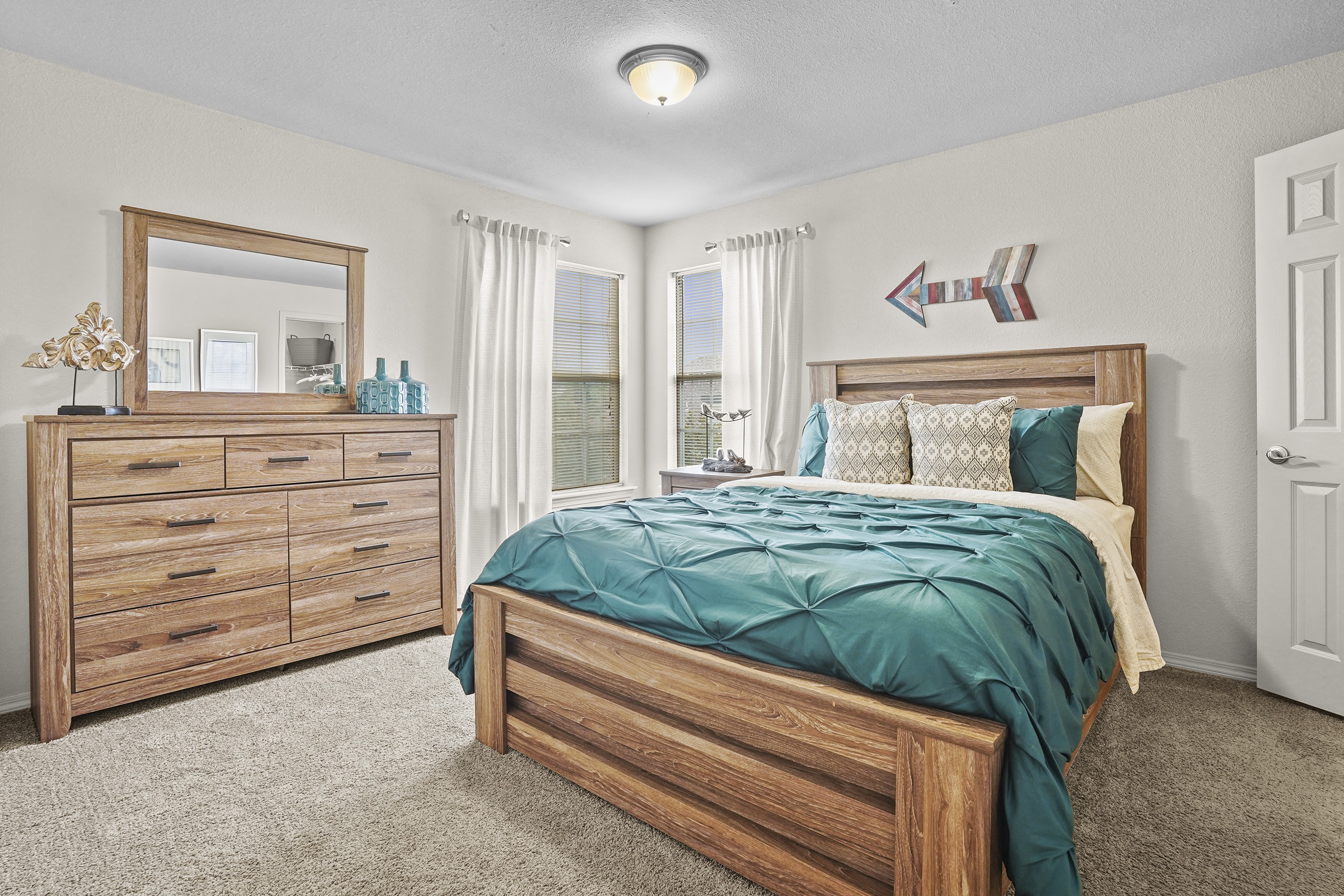 A bedroom with a bed, dresser, and mirror.