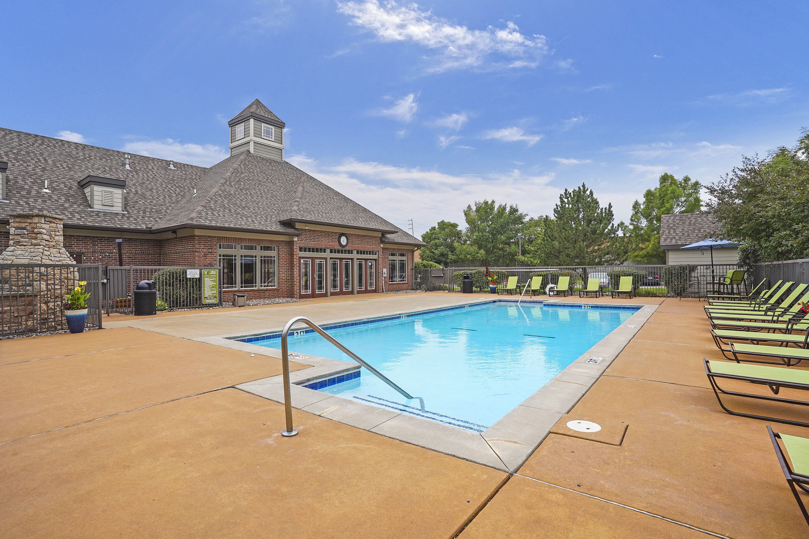 A large outdoor swimming pool with lounge chairs and a building with a tower in the background.