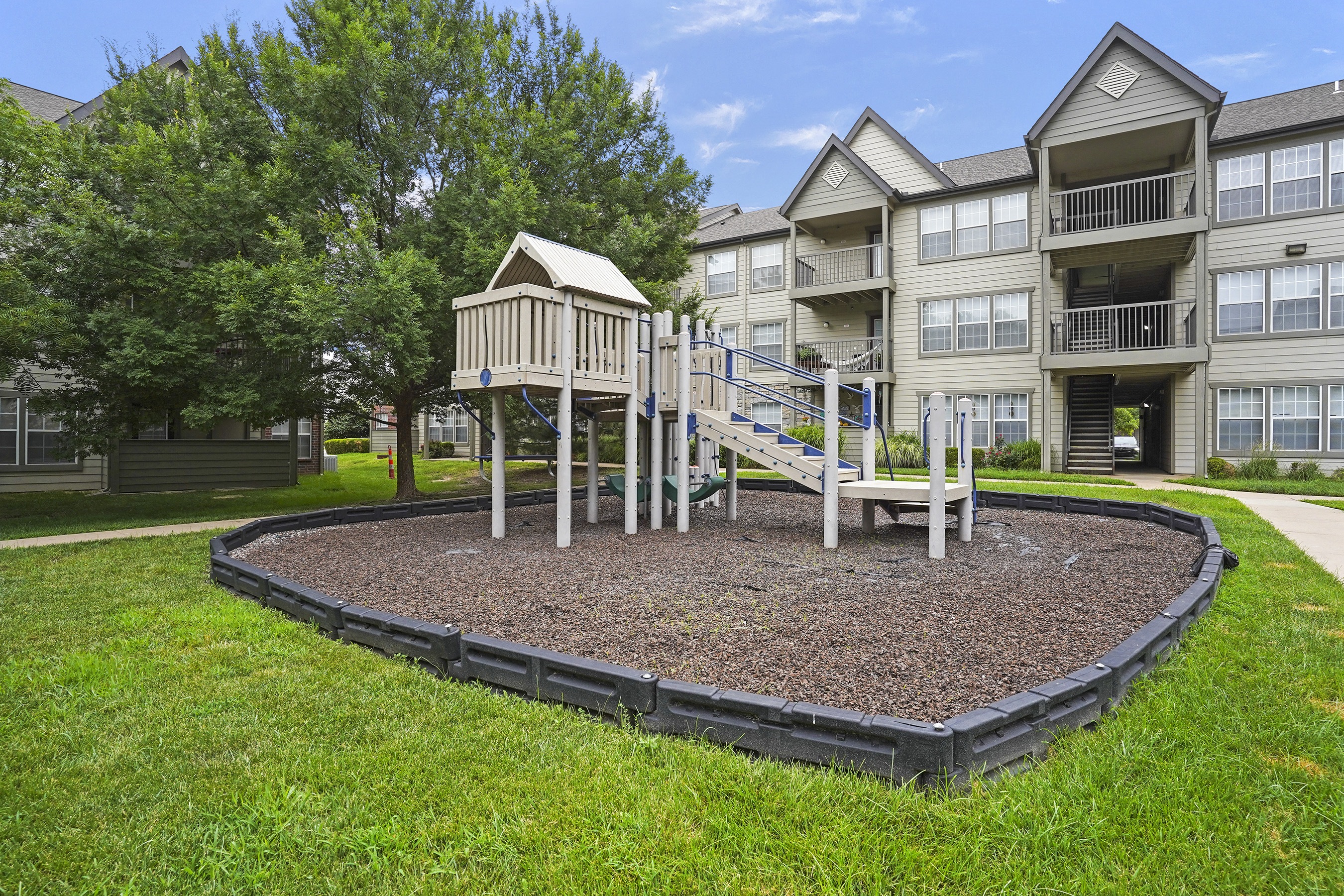 A playground area with a slide and a wooden swing set.